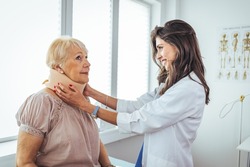 Doctor putting neck orthopaedic collar on adult injured woman. Doctor talking to a senior patient with cervical collar at the hospital. Doctor applying cervical collar on neck of woman in clinic