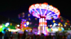 Carnival amusement park ride with swings. Spinning fair ride at night with bright purple red and yellow lights.