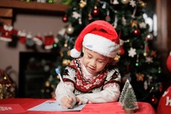 young girl writing letter to Santa against Christmas tree background