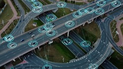 Aerial view: Self-driving autonomous electric cars of the future with HUD elements move along a busy traffic intersection. Concept: Artificial Intelligence, Car Scan, GPS Tracking, Smart Roads, IoT.
