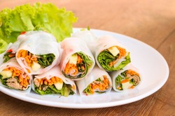 fresh vegetables spring rolls on white plate,  wood table background.
