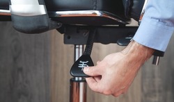 Male hand adjusts office chair.