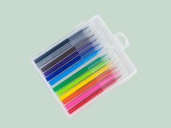 A set of multi-colored markers in a plastic box on a light background. Universal markers for school and office.