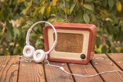 White headphones near an old-fashioned radio on an autumn background. An old technique for listening to radio broadcasts.