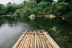Bamboo raft floating in clear river in the forest.