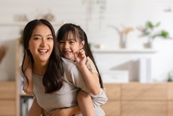 Happy asian mom holding her daughter playing together at home.little girl hugging her mother smile and love having fun at home.Mother day concept
