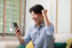 Asian man is smiling and expressing his happy feeling on the cellphone screen. He got good news and show his cheerful face. Technology could helped us have more convenience connection