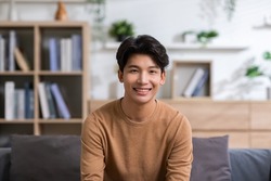 Asian handsome man looking at camera smile at home.Happy young smart businessman smile and confidence.Positive and good moment of asian male worker smile  with wellness life