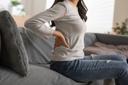 A woman is trying to exercise by twist her upper body, but she has a bit ache and pain on her back. She needs massage and cracking her back to release her tight. She's pushing on the back bone.