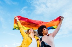 Two women friends hanging out in the city waving LGBT with pride flag