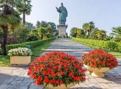 Colorful flowers with the imposing Colossus of San Carlo Borromeo, Arona, Italy in the background