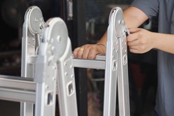 Hand of technician locking Folding Ladder In the open position . convenient ladders ,Light weight, these ladders fold into a compact bundle for storing or carrying.                              