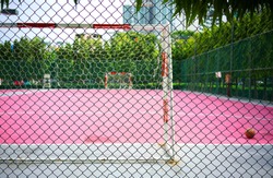 metal wire fence or wire mesh green steel with blur football or pink Futsal Sports Flooring background 