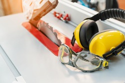 Safety glasses and Earmuffs on Electric saw table in workshop .Work safety concept . selective focus  