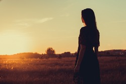 Girl in summer field on sunset background
