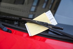 Car with penalty charge notices on the street. Ticket fine on windscreen for parking violation. Parking notice enclosed. Inscription: payment, place and date, stamp, signature.