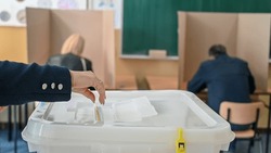 People vote in elections. A woman inserts a ballot into the ballot box.