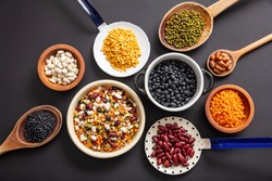 Healthy diet concept.Top view of fflat lay of assortment of legumes pulses on black tabletop background, in scoop, enameled bowl and ladles.