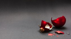 Christmas accident. Red Christmas ball broken, dark gray background, closeup view, copy space