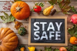 Thanksgiving COVID 19 days. STAY SAFE message  and thanksgiving flatlay on wooden background. Coronavirus protection