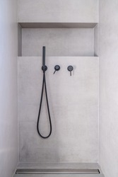 Modern bathroom interior detail with hand shower taps, Shower faucets  black color, on light grey ceramic tile wall background, minimalist design, front view.