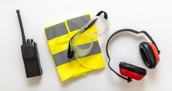 Safety equipment vest glasses, ear muffs and walkie talkie. Work wear protection isolated on white background, Personal protective gear, top view
