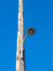 Street light. Retro streetlight, bulb hanging on wooden electric pole. Vintage pillar with lamp. Clear blue sky background