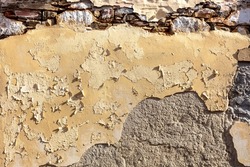 Aged stonewall texture background. Old, worn, distressed stone wall structure, plaster and peeled paint layers