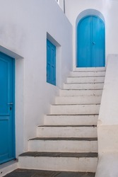 Greece. Traditional architecture in white and blue color. Greek island whitewashed building and stair, wooden door and window. 