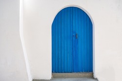 Blue wooden door on white wall background. Greek island house front view. Traditional architecture