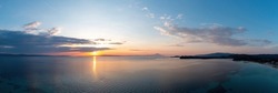Sunrise over calm ocean aerial panoramic view. Dramatic sunset seascape in Aegean Sea. Orange and blue color shades sky. Chalkidiki, Greece