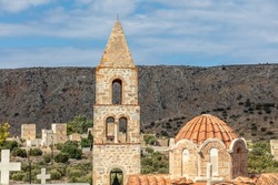 Greece. Ochia village, Mani Laconia, Peloponnese. Byzantine domed  Church of Agios Nikolaos, cemetery church. Belfry, cross, cloudy sky background. Religious destination.