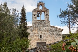 Greece. Limeni village, Mani Laconia, Peloponnese. Greek Orthodox stonewall Church of Agios Nikolaos, cemetery church. Belfry, cross, cloudy sky background. Religious destination.