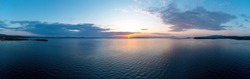 Sunrise over calm ocean aerial panoramic view. Dramatic sunset seascape in Aegean Sea. Orange and blue color shades cloudy sky. Chalkidiki, Greece