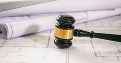 Labor and Construction law concept. Judge gavel on building blueprint plans, close up view.
