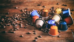 Espresso coffee capsules, pods and coffee beans on wooden background