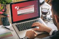 Ransomware alert message on a laptop screen - man at work