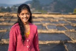 Portrait of a young indian village girl wearing winter clothes and smiling into the camera.