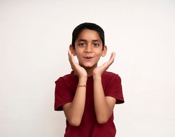 Young Indian kid acting surprised white standing on a white wall with copy space. Education and fun concept.