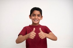 Young indian kid showing thumbs up into the camera while smiling. Small kid education concept.