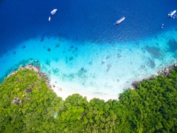 Isolated beautiful tropical island with white sand beach and blue clear water and granite stones. Top view, speedboats above coral reef. Similan Islands, Thailand.