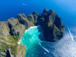 Top view of tropical island with limestone rocks, white beach and blue clear water. Aerial view of Maya bay with many boats and speedboats above coral reef. Phi-Phi Islands, Krabi, Thailand.