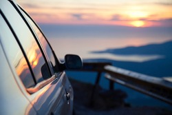 Road trip by car at sunset. Parking on roadside of narrow mountain way. Stop for rest. View of amazing sea coastline. Concept of outdoor adventure, summer vacation. Copy space