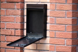 Open metal mailbox on brick wall. Close-up. Selective focus.
