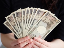 A woman holding a 10,000 yen bill for 100,000 yen