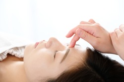 A woman who receives acupressure between eyebrows in an acupuncture clinic