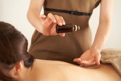 An esthetician dripping massage oil at an aesthetic salon