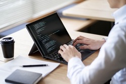 Asian programmer writing code on a laptop