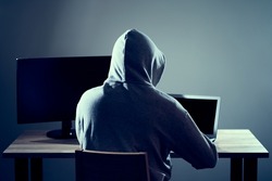 Male hacker writing code on a laptop