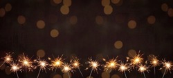 Holiday New Year's Eve Silvester New Year Party Birthday Wedding festive background banner greeting card	- Many burning sparkler in the dark black night with bokeh golden light